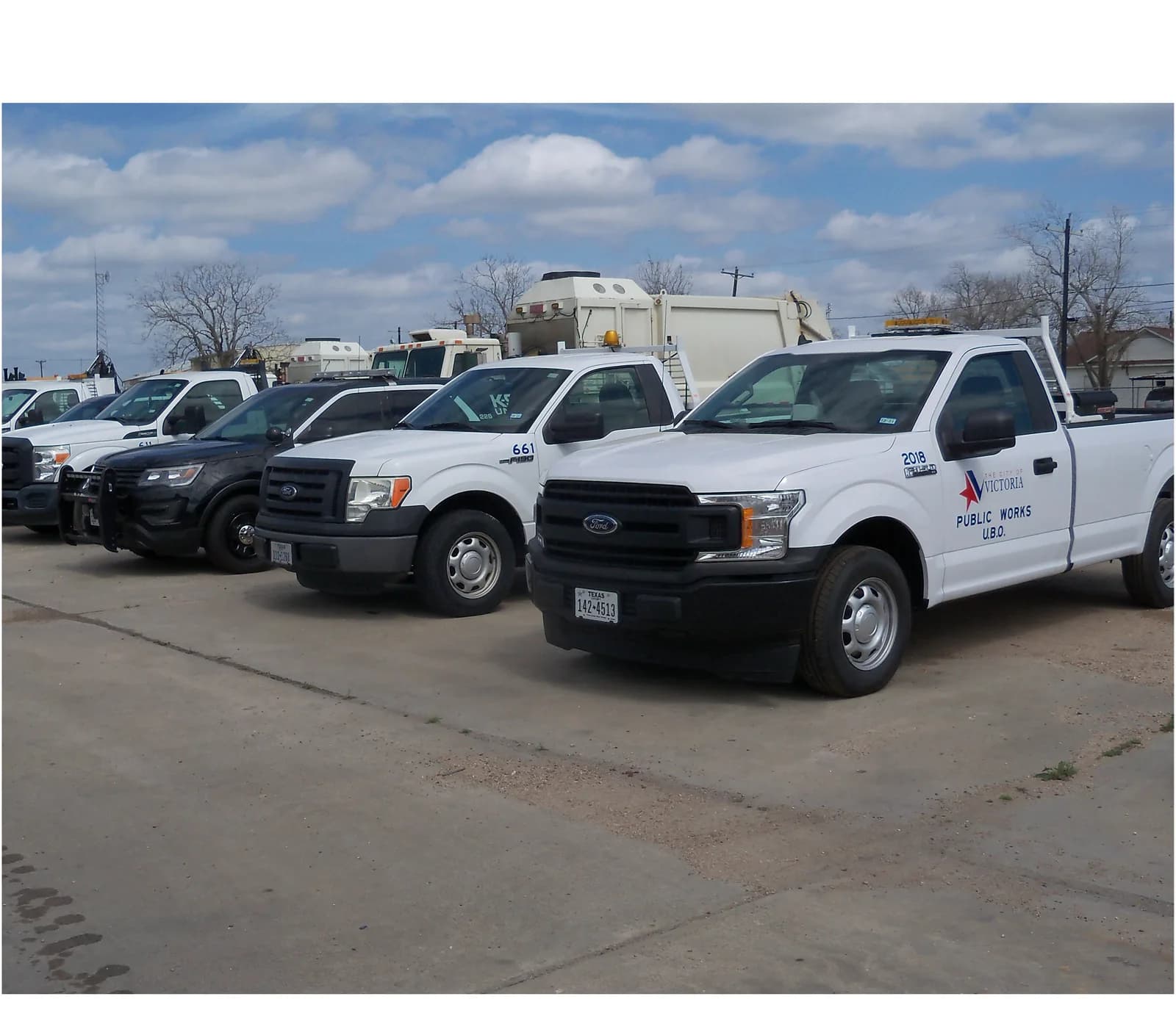 A fleet of municipal public works pickup trucks parked in a lot
